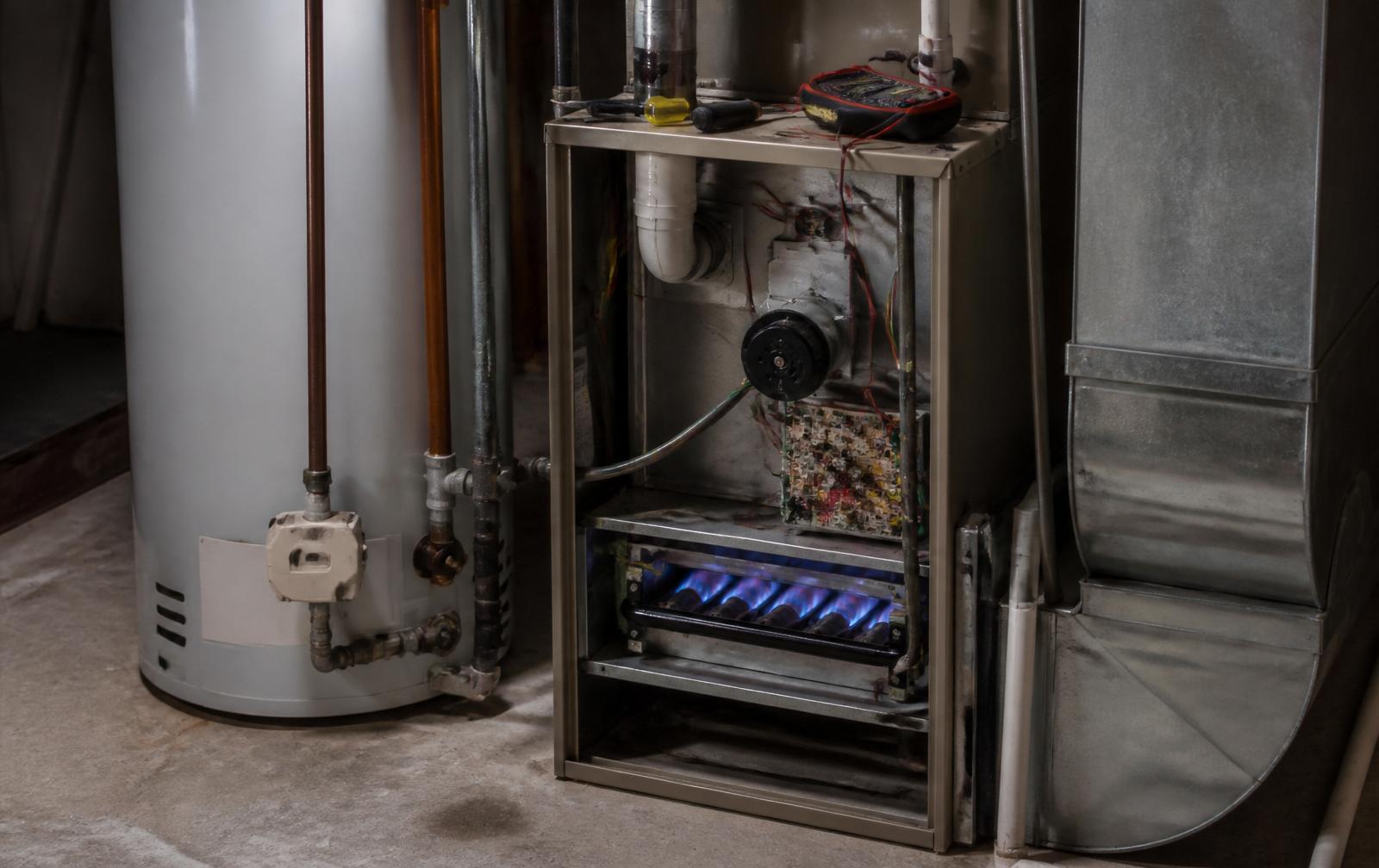 Residential natural gas furnace with front panel off and burners lit during a fall tune-up in Powder Springs